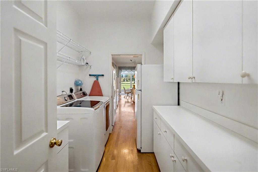Laundry room featuring cabinet space, light wood finished floors, and independent washer and dryer