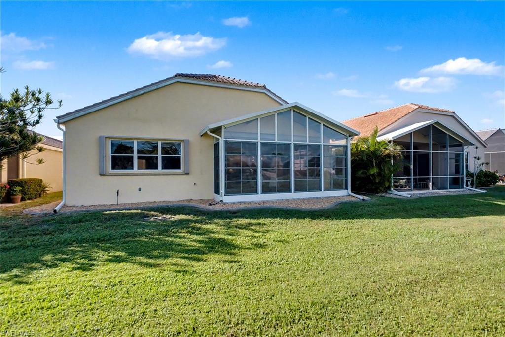 Back of property with stucco siding, a yard, and a sunroom