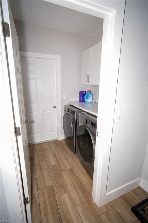 Laundry room with wood tiled floors, cabinet space, and washer and clothes dryer