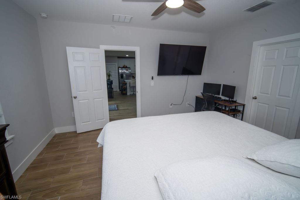 Bedroom with wood tiled floors, an office area, and ceiling fan