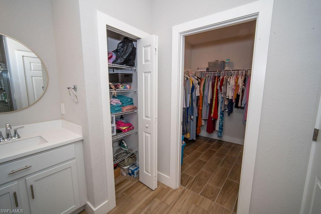 Bathroom featuring a spacious closet, wood tiled floors, and vanity