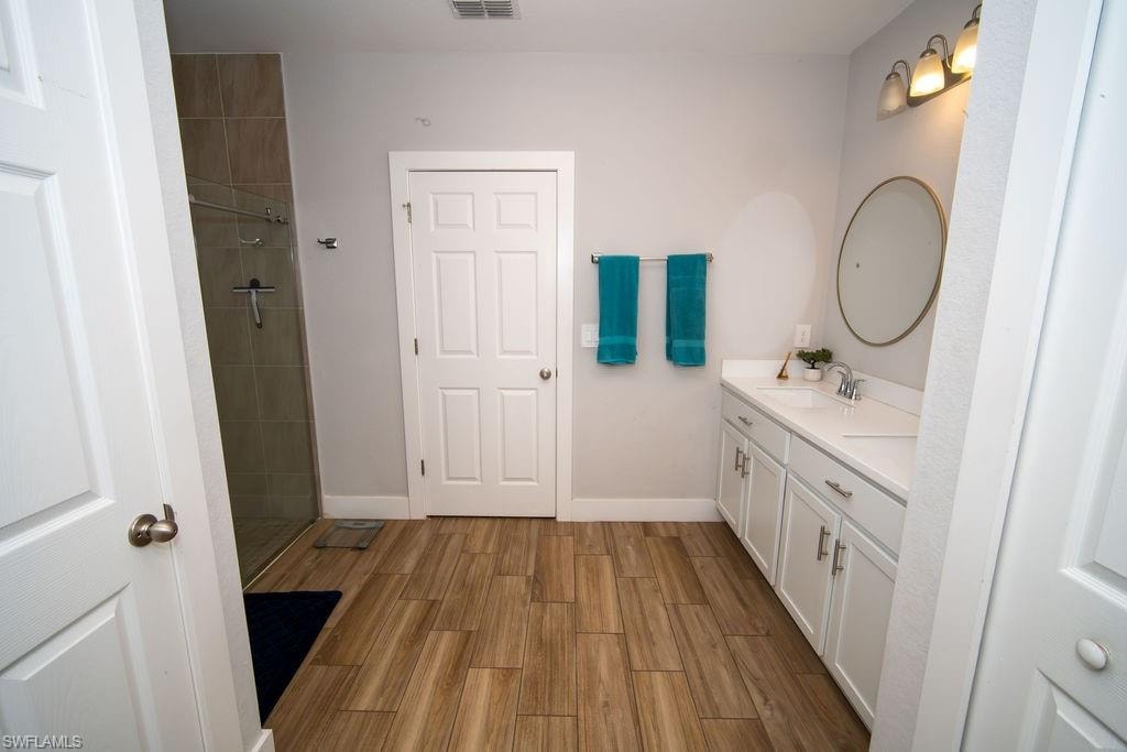 Bathroom with double vanity, a shower stall, and wood tiled floors