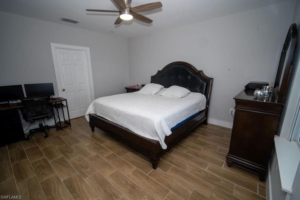 Bedroom featuring wood tiled floors, an office area, and a ceiling fan