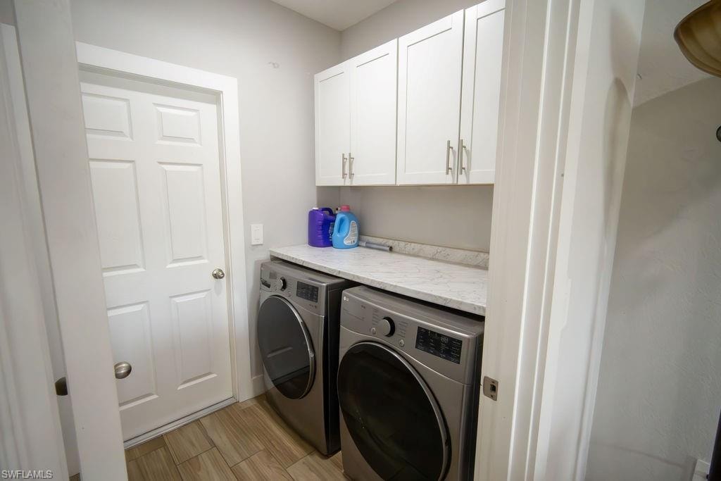 Washroom with cabinet space, washing machine and dryer, and light wood-type flooring