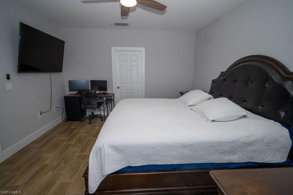 Bedroom featuring wood finish floors, a ceiling fan, and an office area