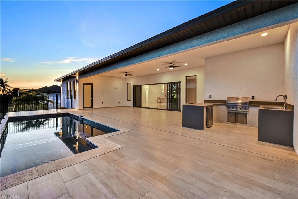 Pool at dusk with area for grilling and a patio area