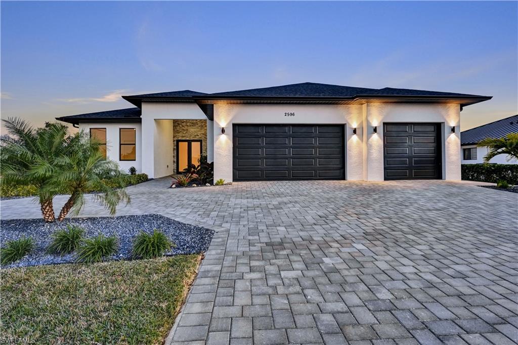 Prairie-style house with stucco siding, decorative driveway, and a garage
