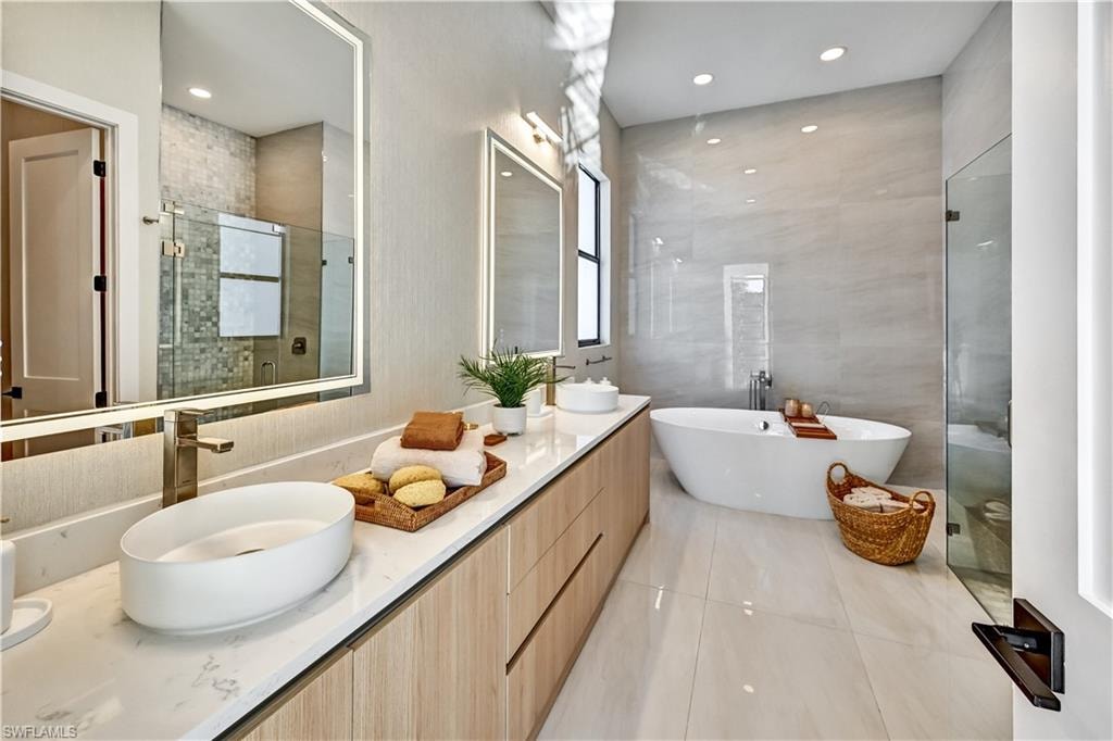 Full bath with a stall shower, double vanity, a freestanding tub, recessed lighting, and light tile patterned floors