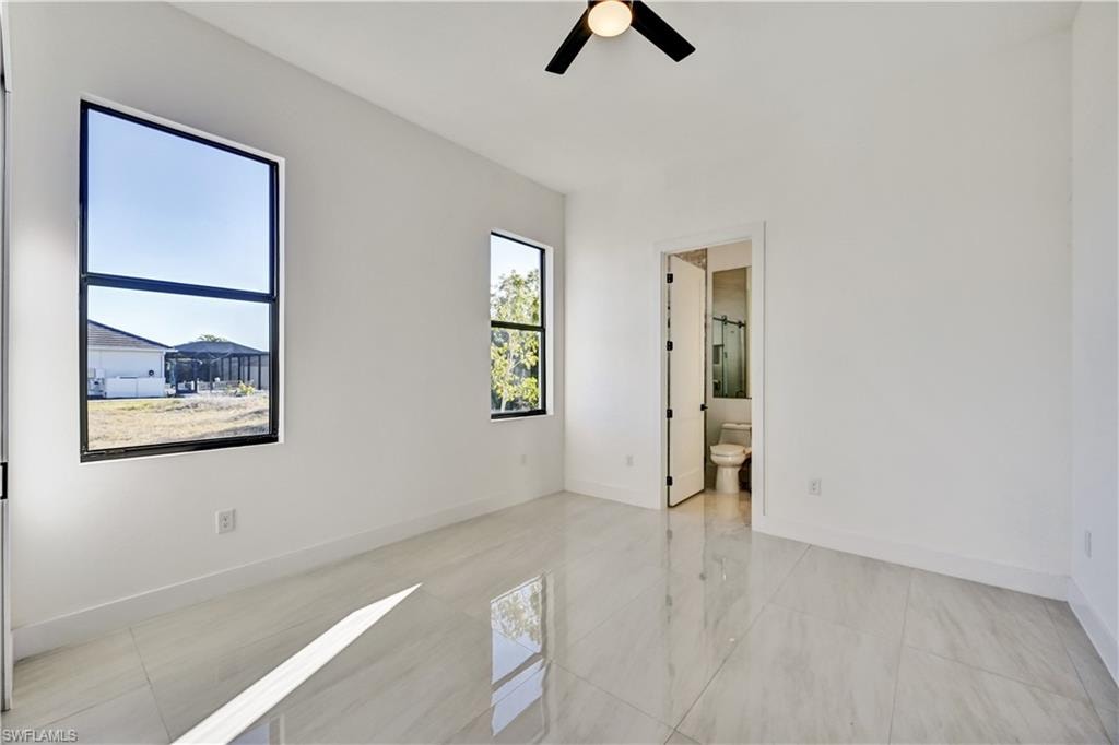 Unfurnished bedroom featuring ceiling fan and ensuite bathroom