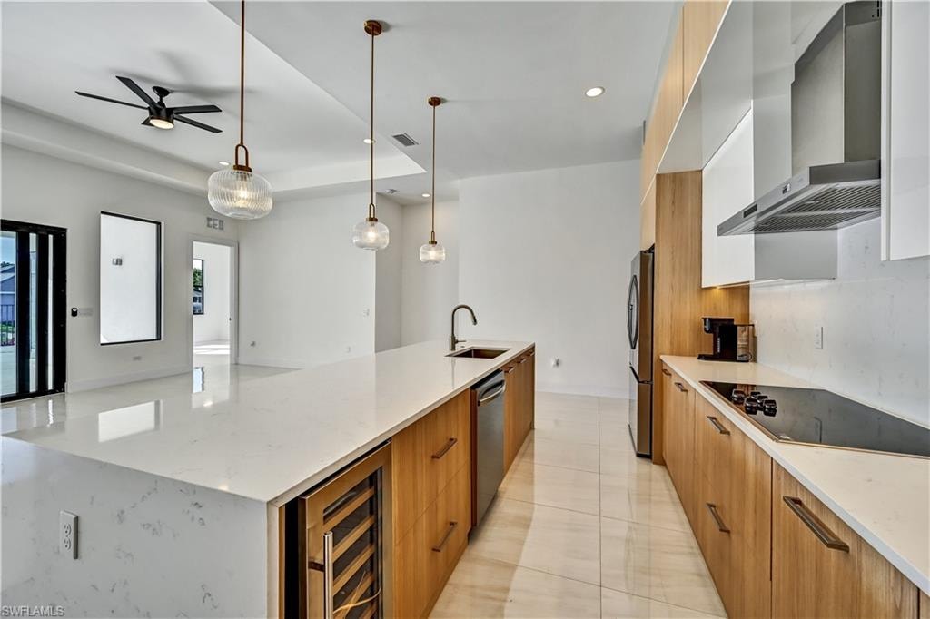 Kitchen with modern cabinets, light stone countertops, a large island with sink, two tone cabinets, and stainless steel appliances
