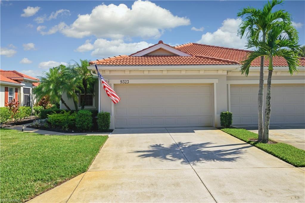 Mediterranean / spanish house featuring a tile roof, driveway, stucco siding, and a front lawn