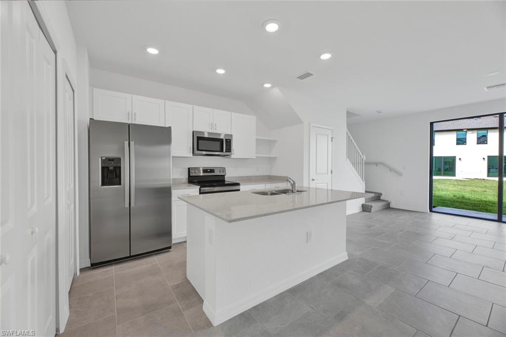 Kitchen featuring appliances with stainless steel finishes, open shelves, white cabinetry, recessed lighting, and light stone countertops
