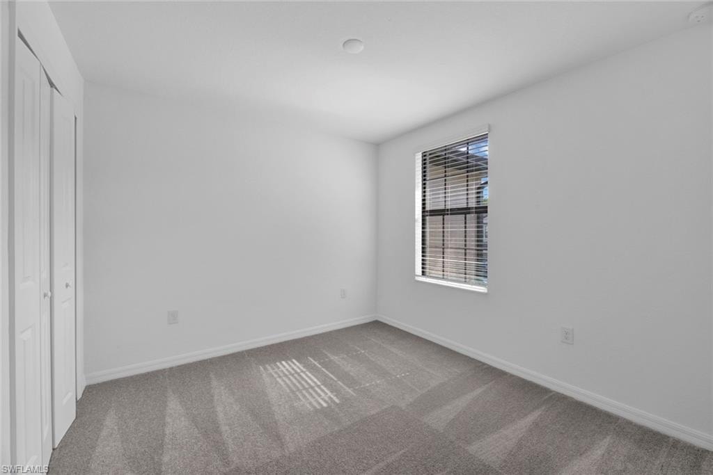 Unfurnished bedroom with light carpet and a closet