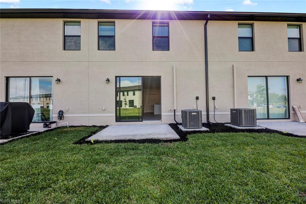 Rear view of house featuring a patio area, a lawn, and stucco siding