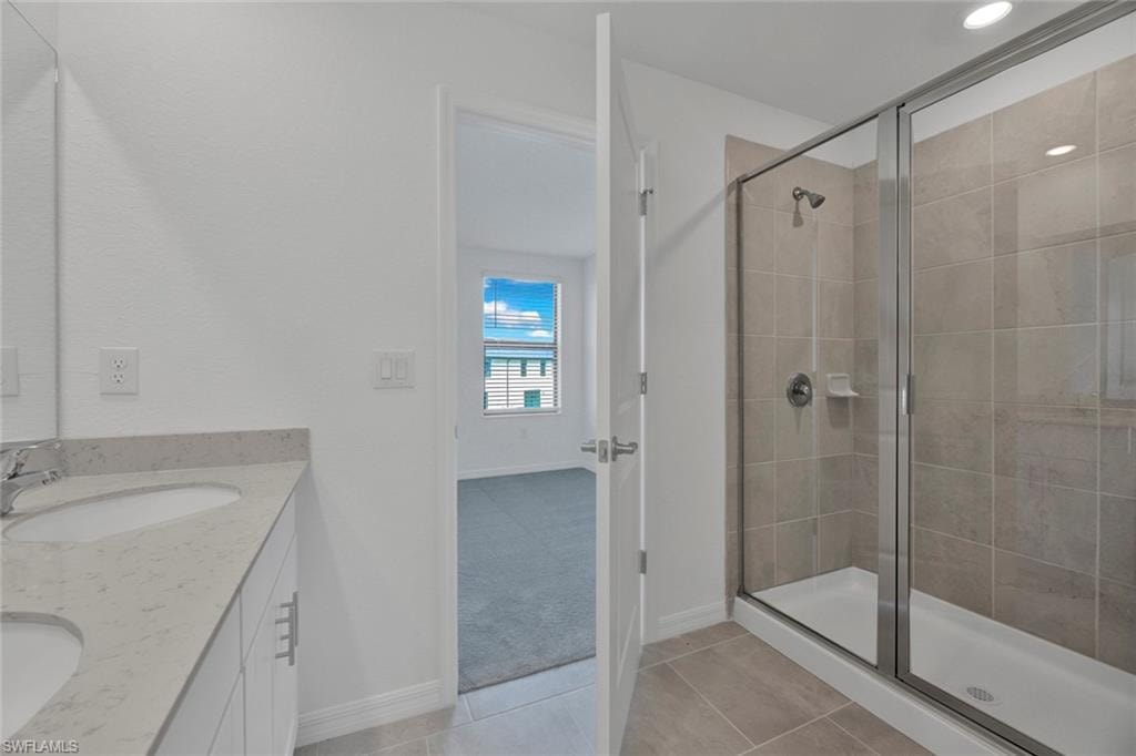 Full bathroom with light tile patterned flooring, double vanity, and a stall shower