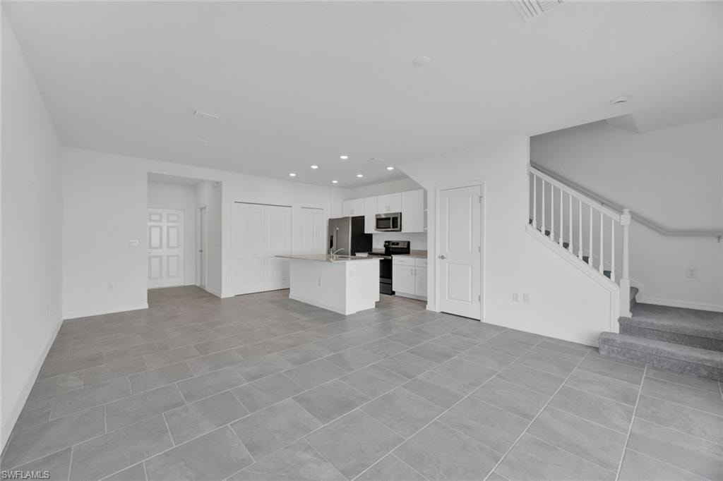 Unfurnished living room with stairway, recessed lighting, and light tile patterned floors