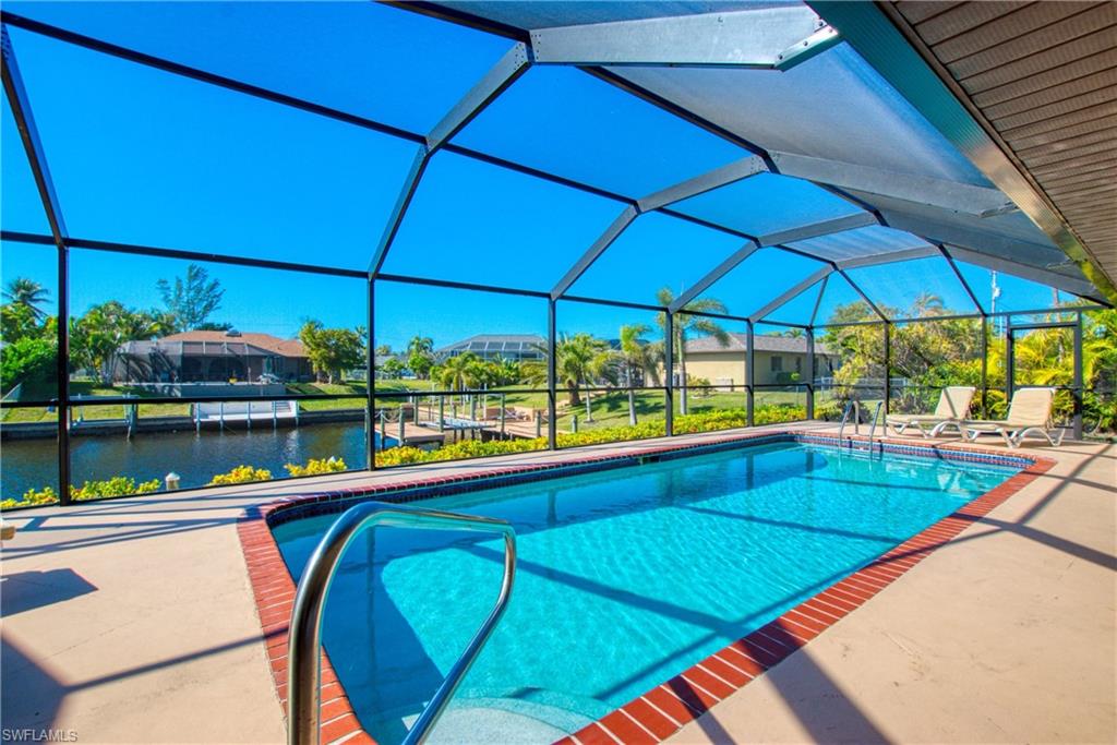 Swimming pool with a lanai, a sunroom, a water view, and a patio