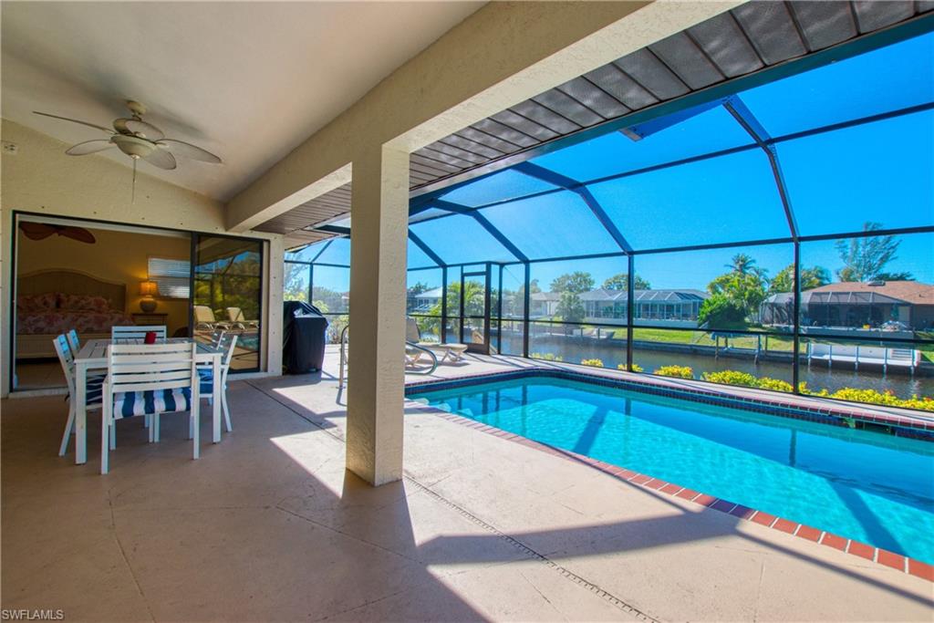 Outdoor pool with a sunroom, a patio area, glass enclosure, outdoor dining space, and ceiling fan