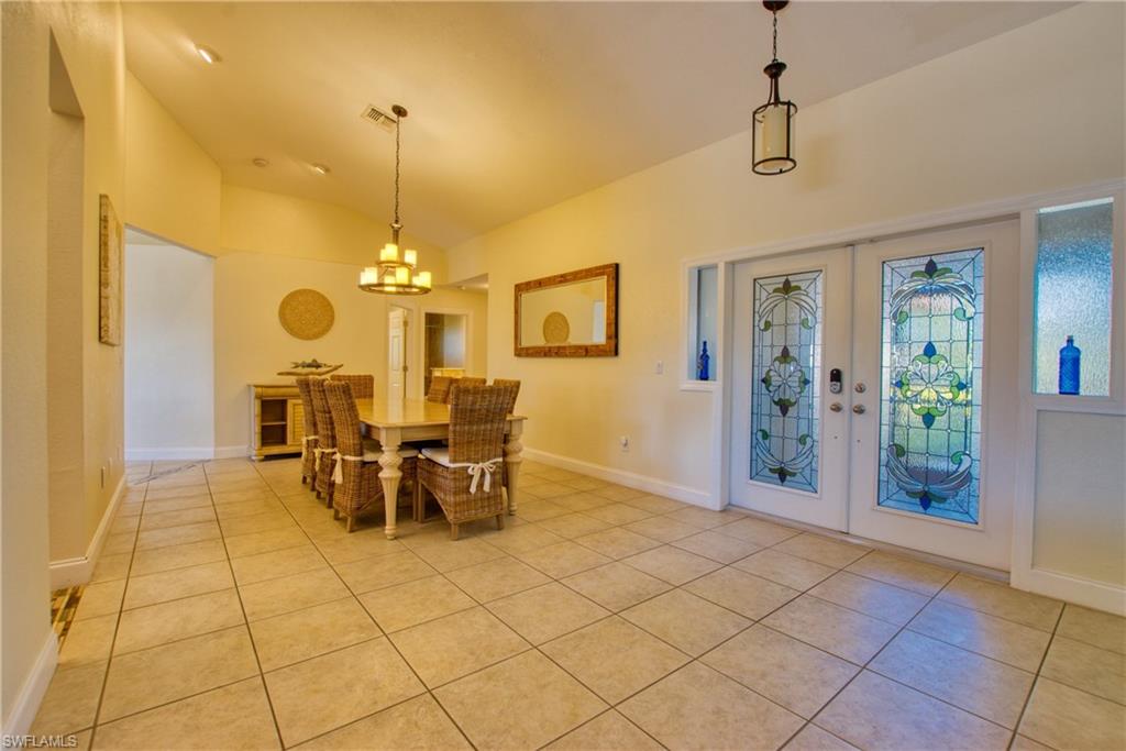 Dining room featuring french doors, light tile patterned flooring, lofted ceiling, and a chandelier