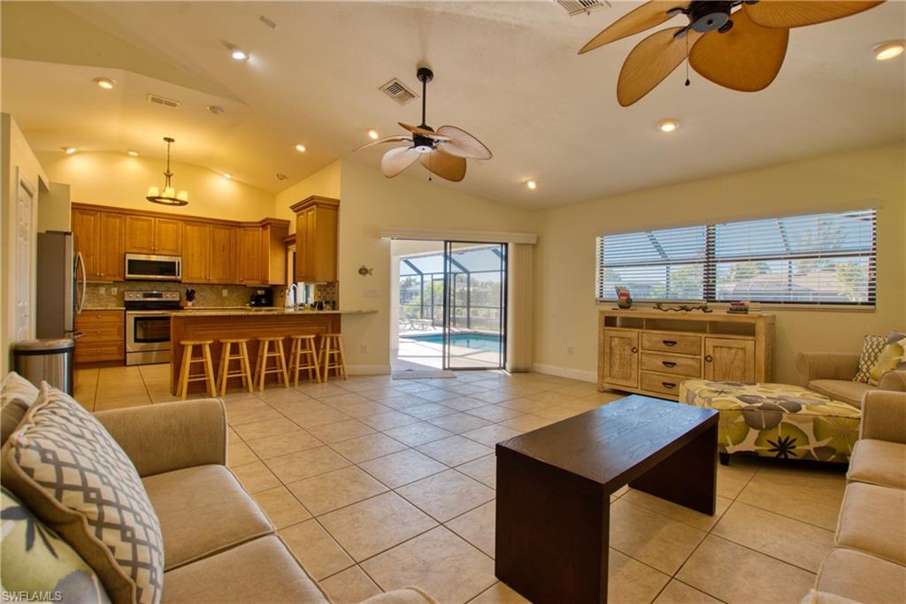 Living area with lofted ceiling, light tile patterned floors, recessed lighting, and ceiling fan