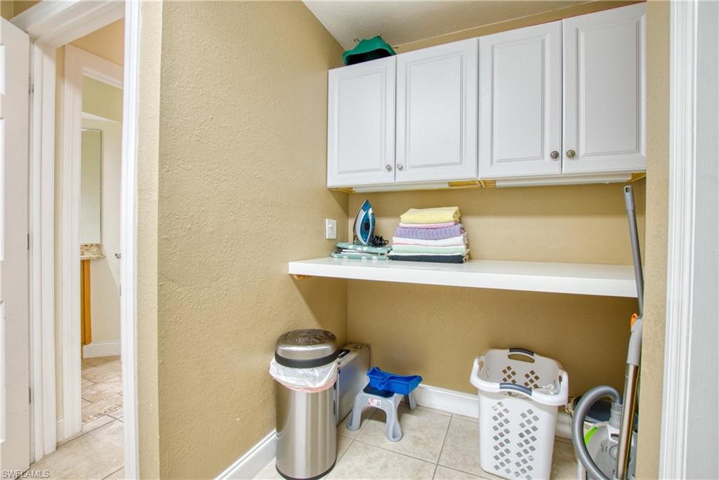 Laundry area featuring a textured wall and light tile patterned floors