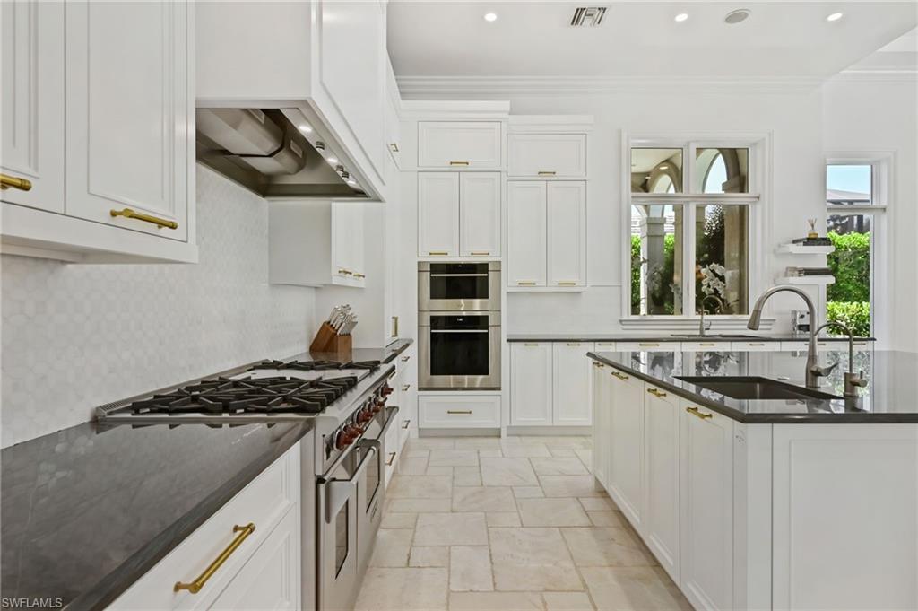 Kitchen featuring appliances with stainless steel finishes, dark stone countertops, white cabinetry, recessed lighting, and decorative backsplash