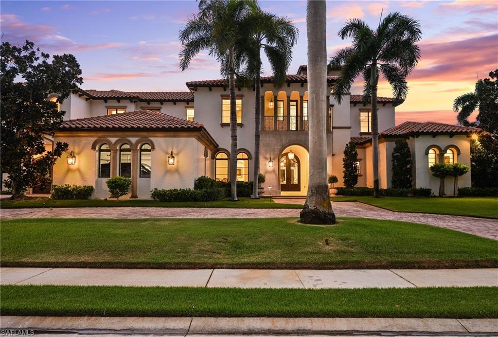Mediterranean / spanish home featuring a front yard, stucco siding, and driveway
