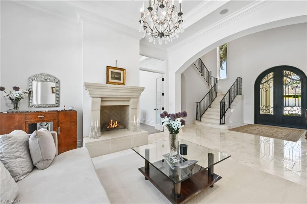 Living room with ornamental molding, a fireplace, a high ceiling, french doors, and a chandelier