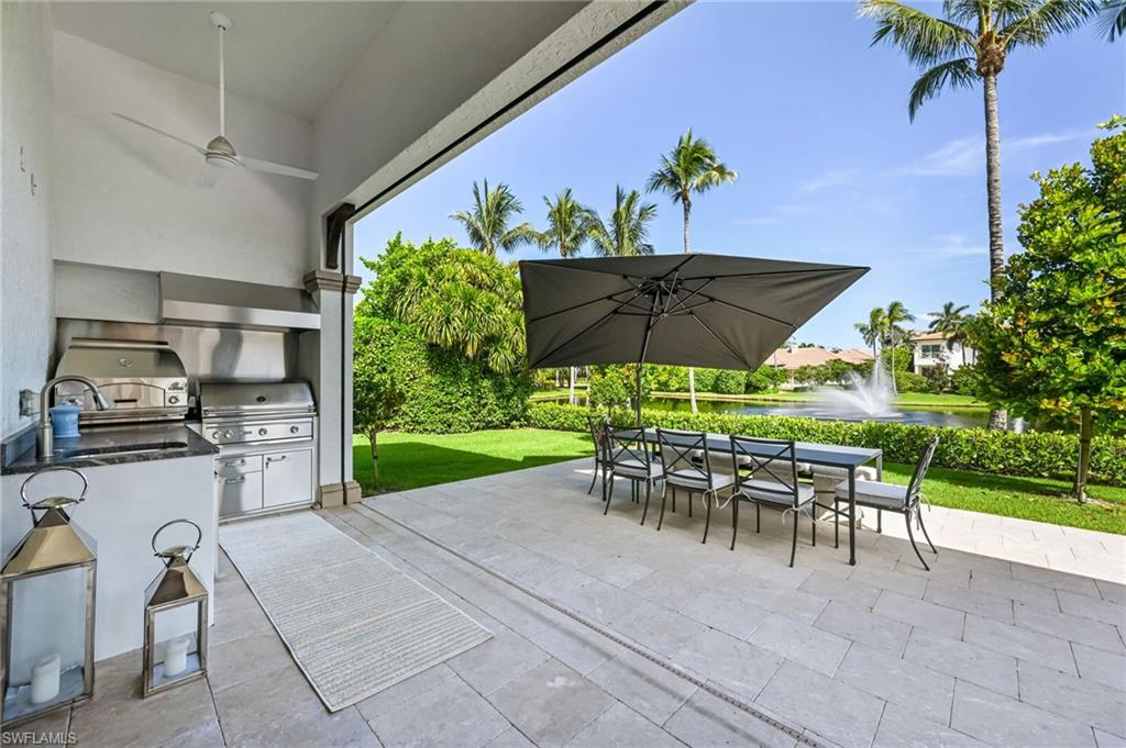 View of patio with outdoor dining area, a ceiling fan, an outdoor kitchen, and a water view