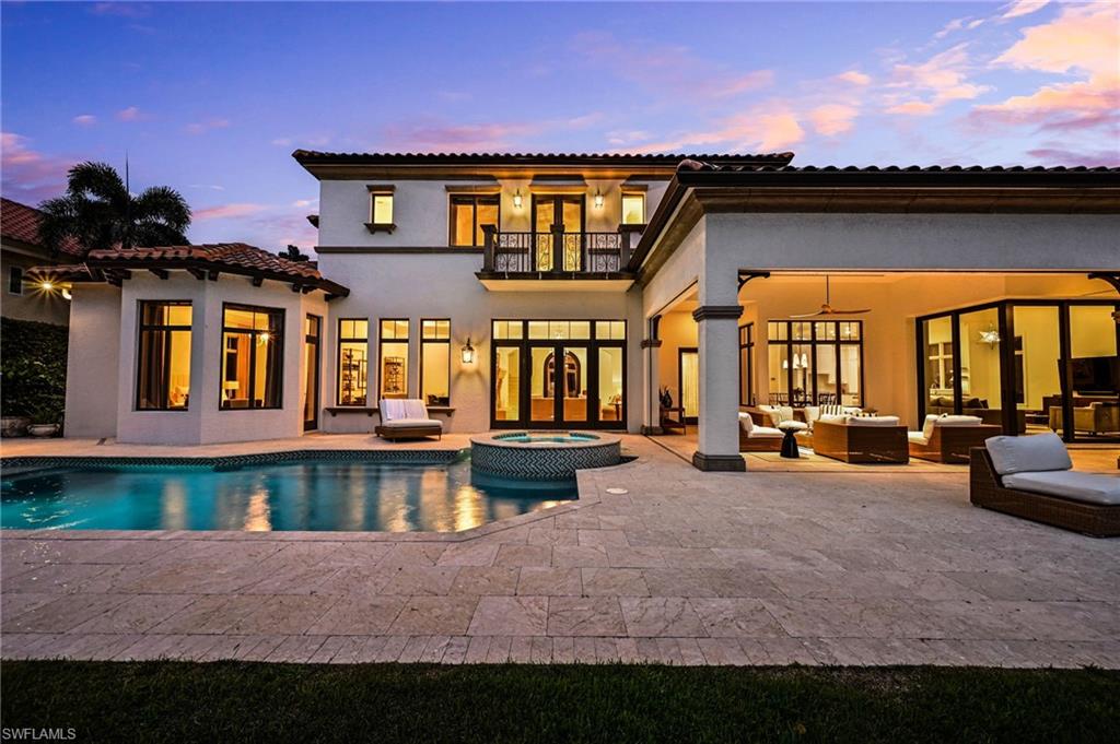 Back of property with a balcony, a patio, a pool with connected hot tub, and stucco siding