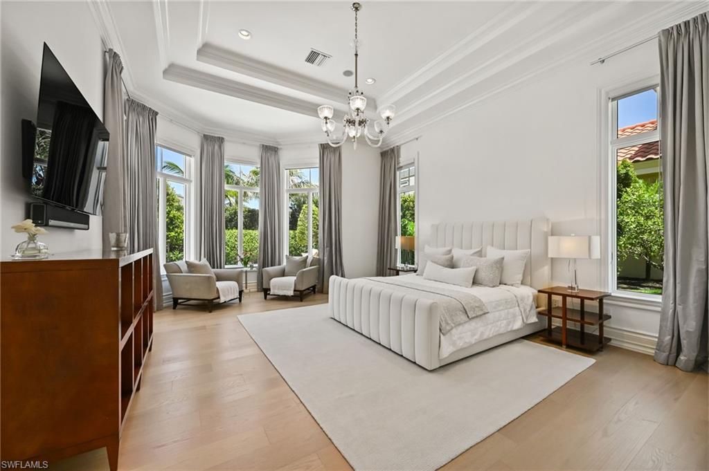 Bedroom with light wood-style floors, multiple windows, a chandelier, ornamental molding, and recessed lighting