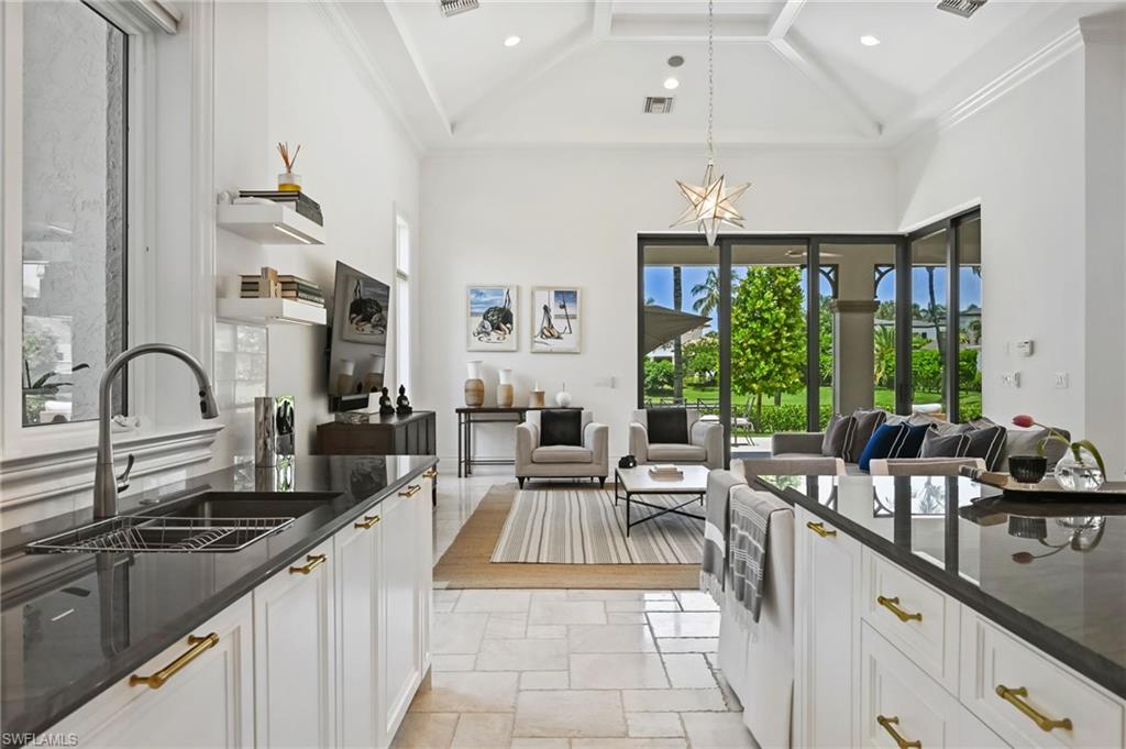 Kitchen featuring white cabinetry, dark stone counters, high vaulted ceiling, open floor plan, and hanging light fixtures