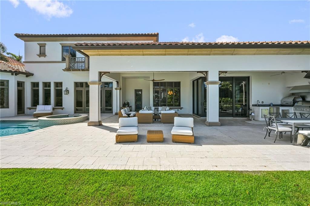 Rear view of house with an outdoor kitchen, a ceiling fan, a patio area, and a pool with connected hot tub