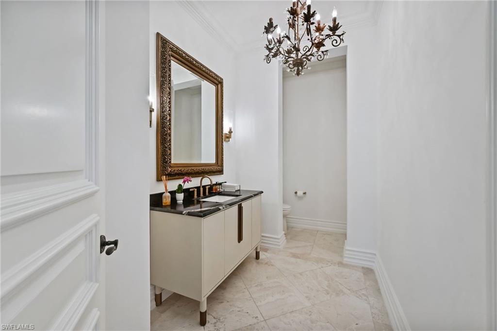 Bathroom featuring ornamental molding, a chandelier, vanity, and light tile patterned flooring