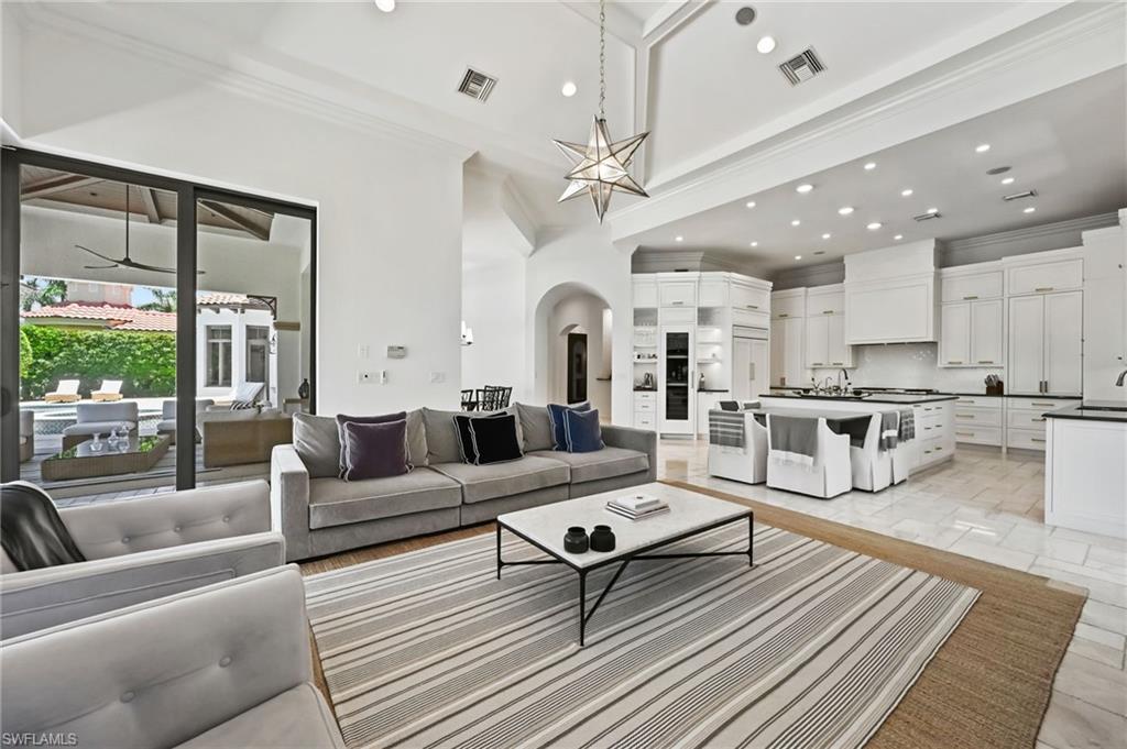 Living room featuring crown molding, arched walkways, recessed lighting, and a high ceiling