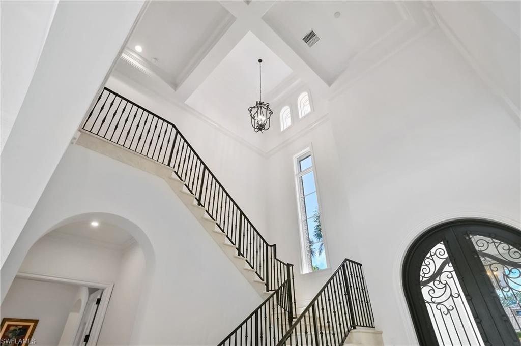 Foyer entrance featuring a towering ceiling, arched walkways, a chandelier, french doors, and stairway
