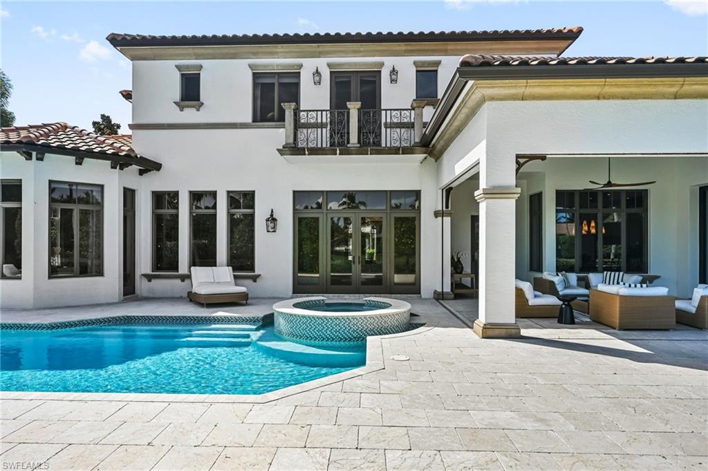 Rear view of property featuring a balcony, french doors, an outdoor living space, and a pool with connected hot tub