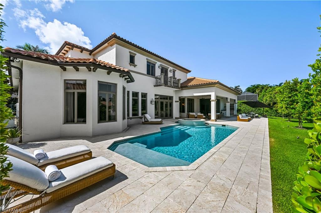 Rear view of house featuring stucco siding, a pool with connected hot tub, a patio, a tile roof, and a balcony