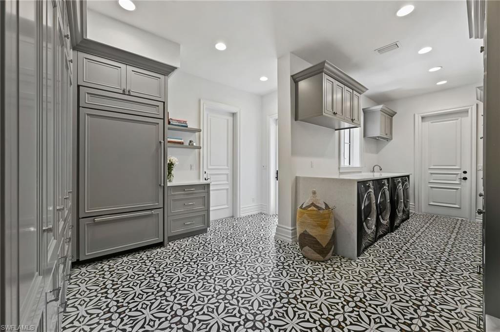 Kitchen with gray cabinetry, paneled built in fridge, recessed lighting, washing machine and dryer, and open shelves