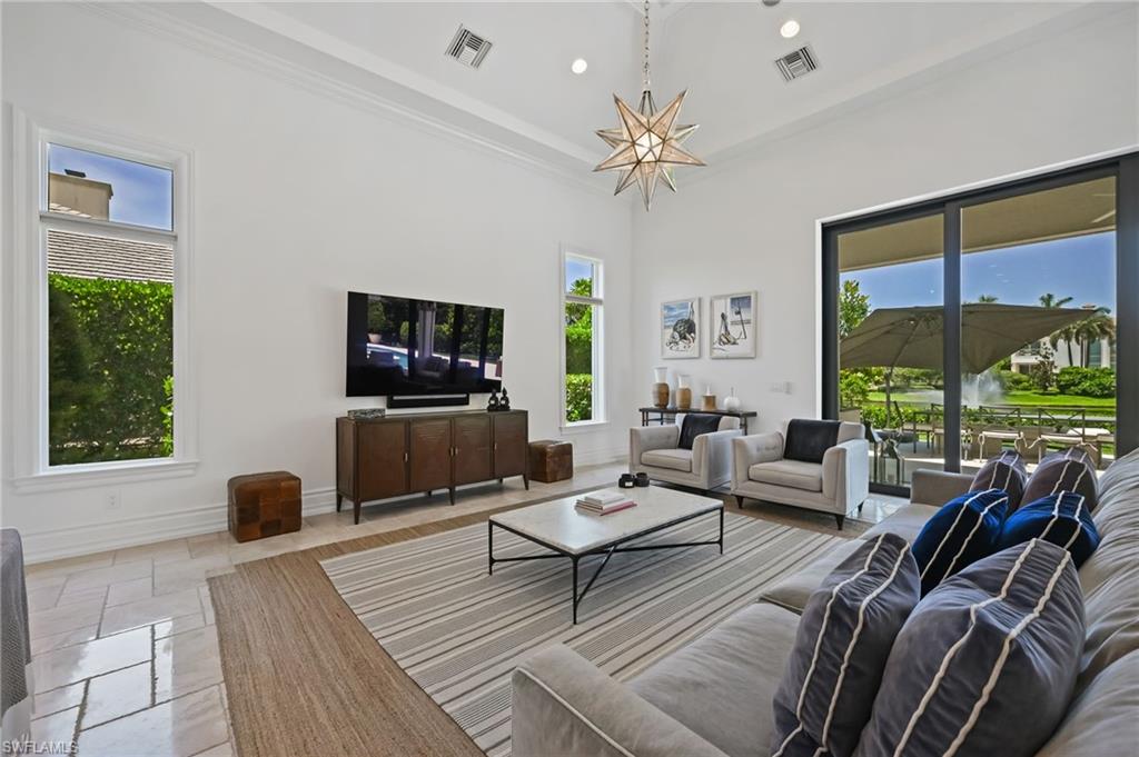 Living room with recessed lighting, plenty of natural light, a high ceiling, and crown molding