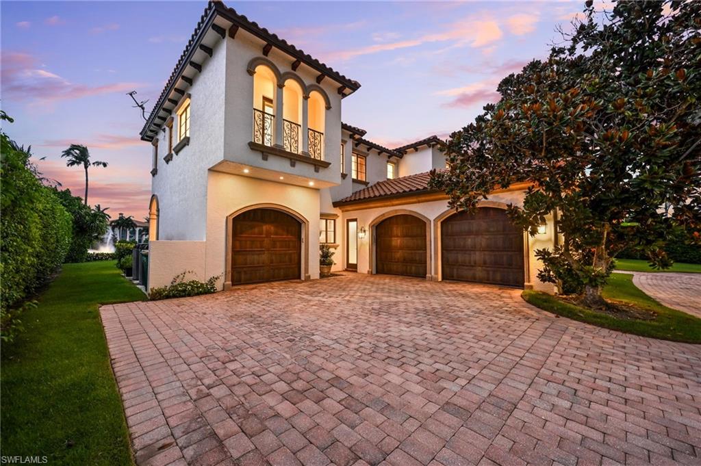 Mediterranean / spanish-style home featuring decorative driveway, a balcony, stucco siding, and a yard