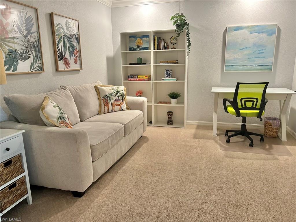 Home office featuring a textured wall, light colored carpet, and crown molding