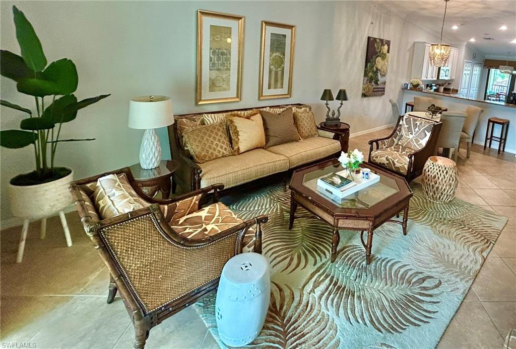 Living room featuring light tile patterned flooring, hanging lights, and crown molding