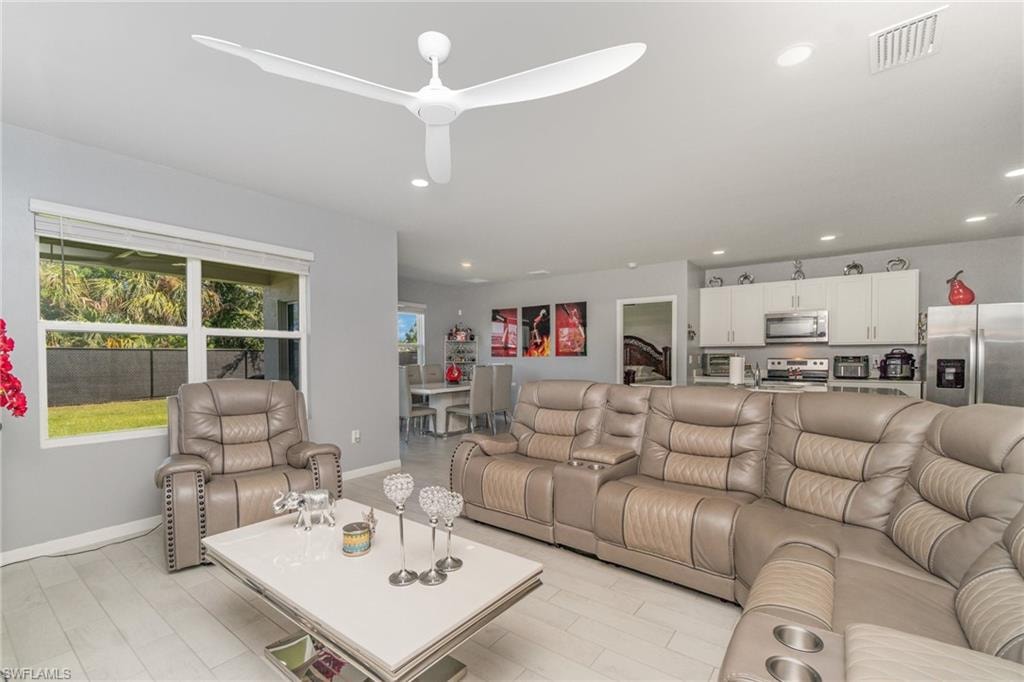 Living room with recessed lighting, a ceiling fan, and light wood-style floors