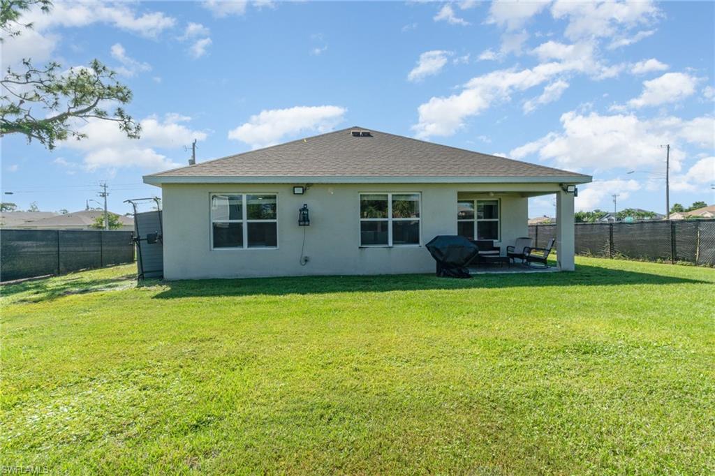 Back of house featuring a fenced backyard, stucco siding, a patio area, and roof with shingles