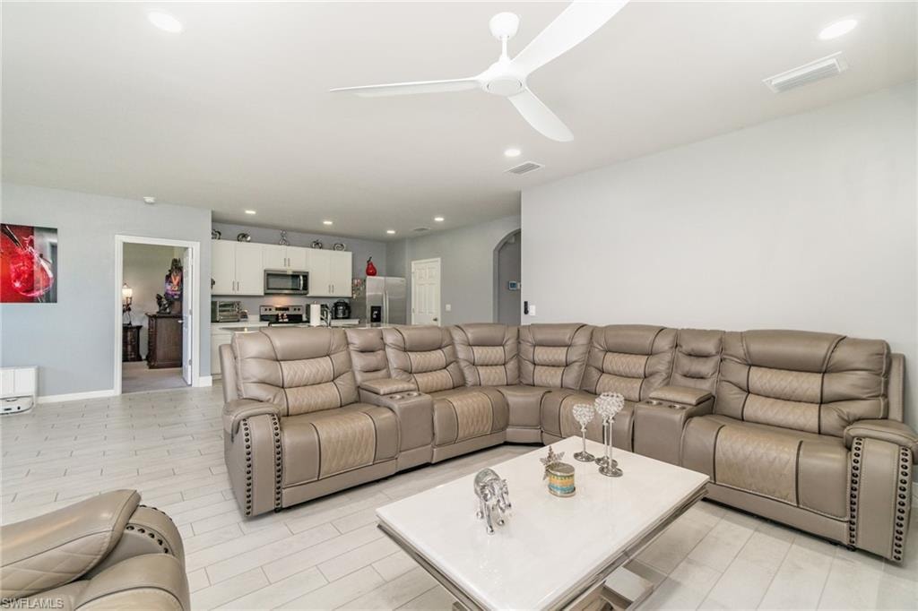 Living area with arched walkways, recessed lighting, and ceiling fan