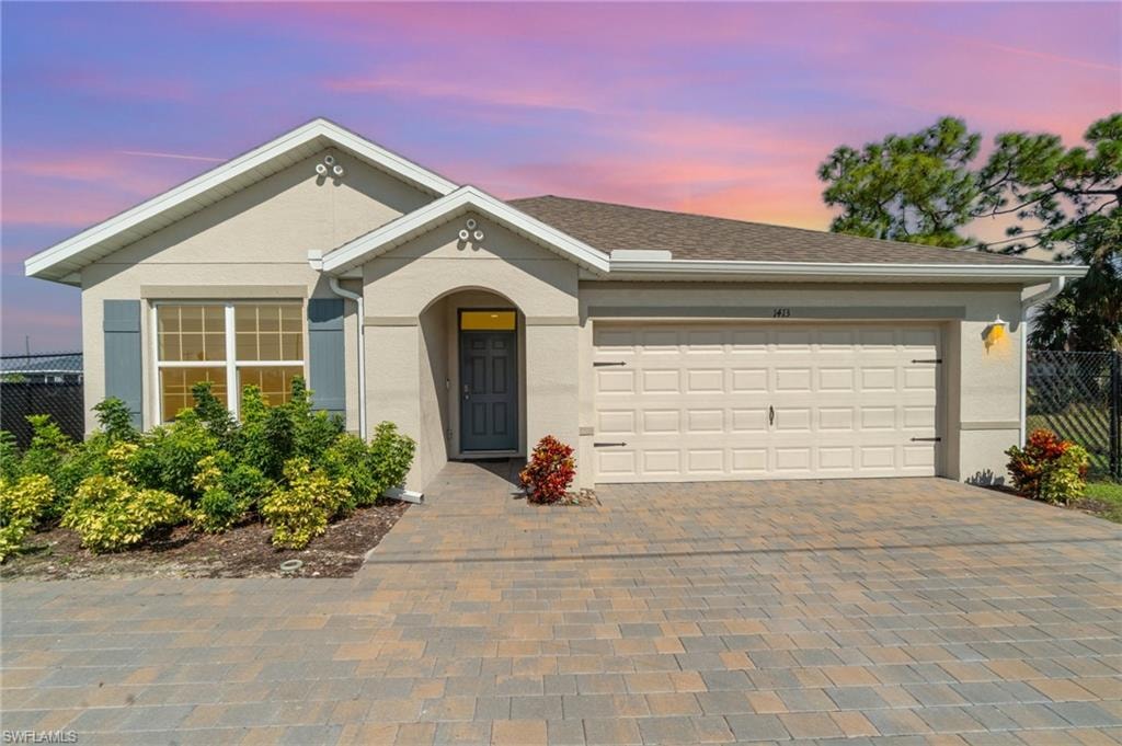 Ranch-style house with decorative driveway, an attached garage, and stucco siding