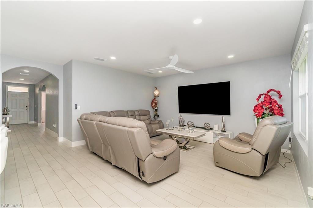 Living area featuring arched walkways, recessed lighting, ceiling fan, and light wood-style floors