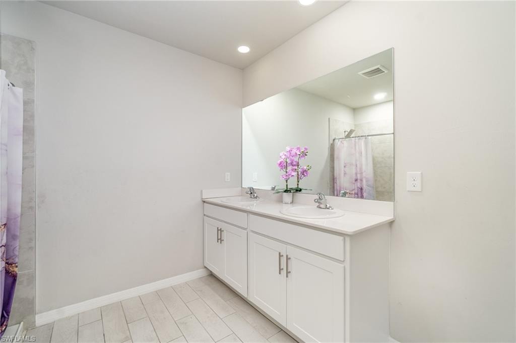 Full bath featuring double vanity and a shower with curtain