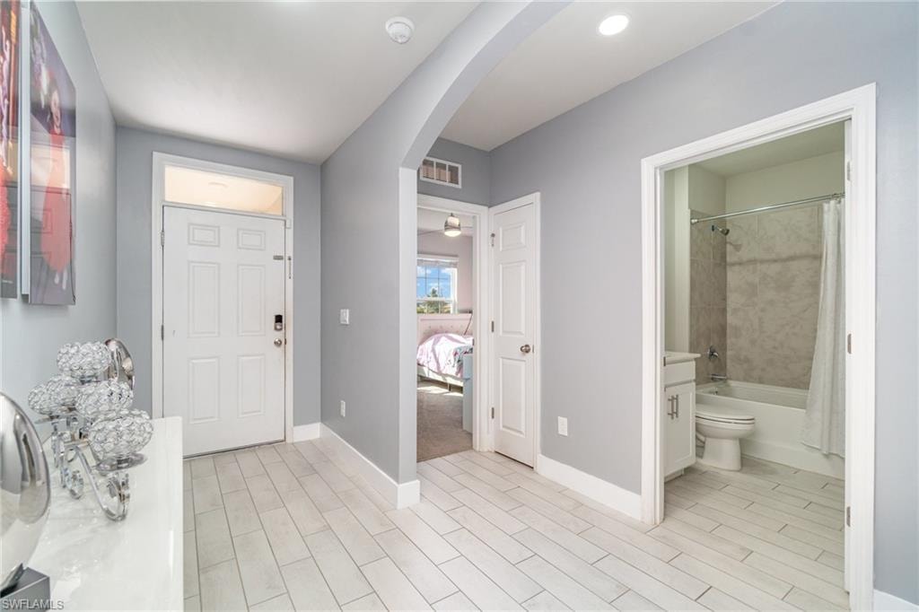 Foyer with arched walkways and wood finish floors